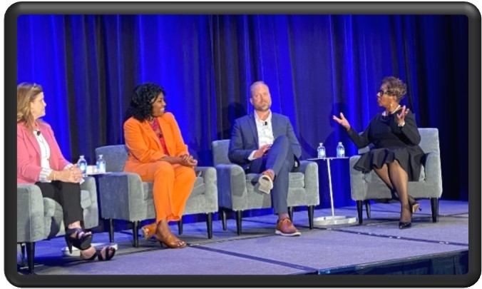 Photo of Commissioner Dorantes participating in a panel discussion with three others.  The Commissioner wears a bright orange outfit.