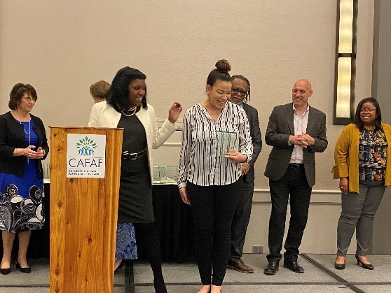 Gabbie receiving an award from Commissioner Dorantes with other Exec Team members smiling in the background