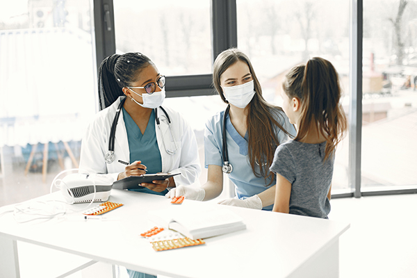 Nurses and healthcare workers assisting child in a healthcare setting.