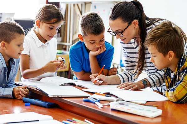 Teacher reviewing homework with children.